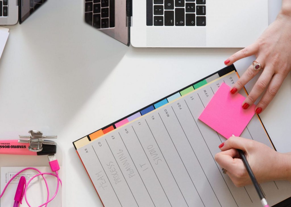 Secrétaire écrivant sur un post-it par-dessus un trieur