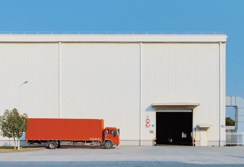 Camion rouge de transport à côté d'une entrée d'entrepôt