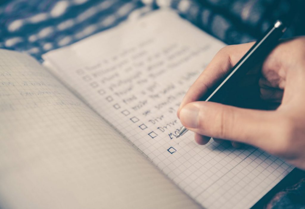 Main écrivant une checklist sur un cahier